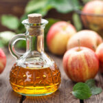bottle of apple cider vinegar with apples