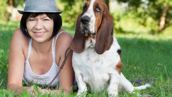 basset hound in park with middle-age woman