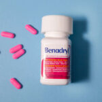 Benadryl bottle and pills on blue background