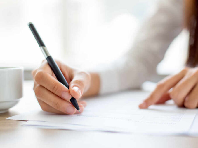 woman writing on paper on a desk